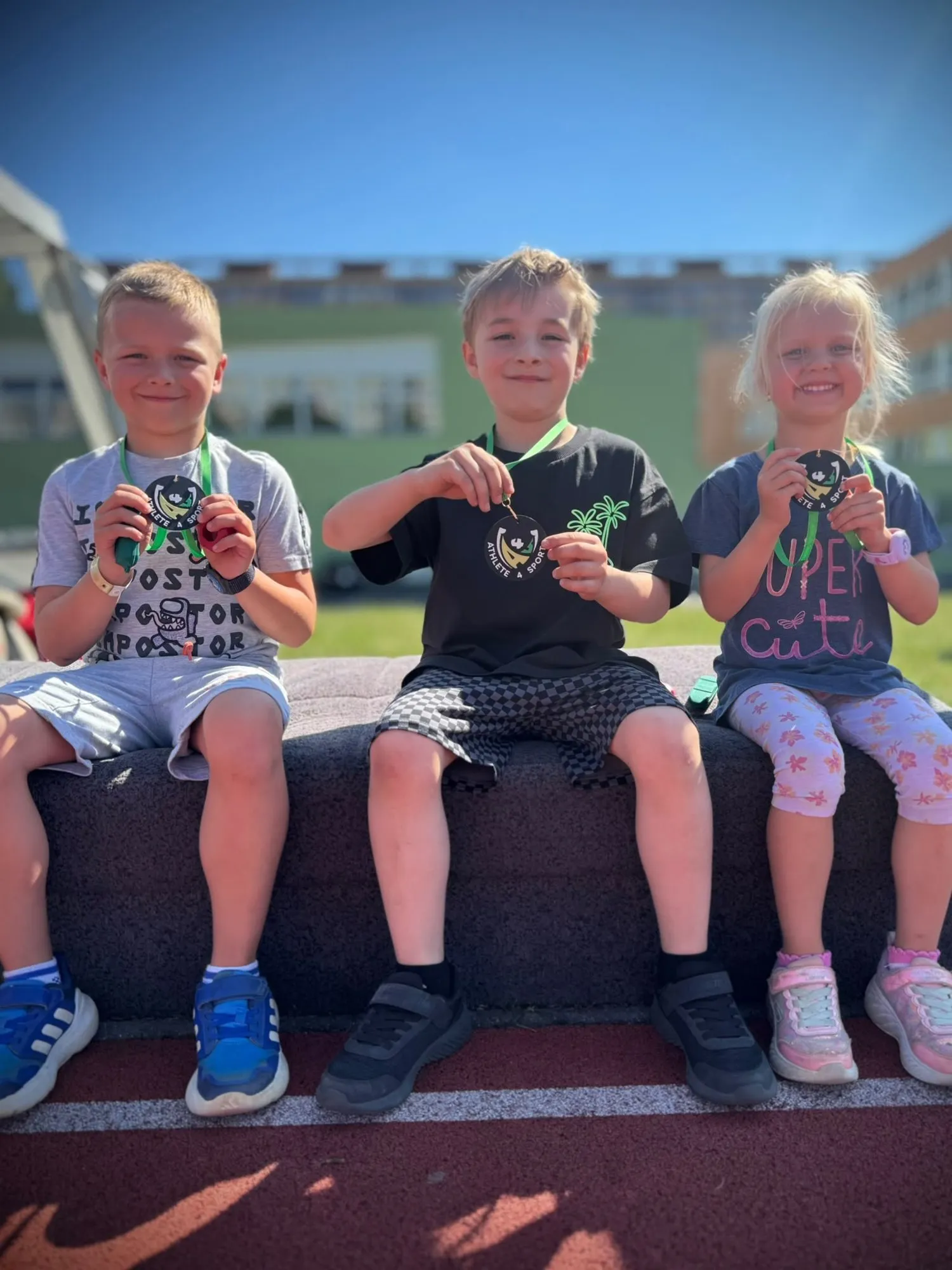 Tři děti s medailemi Athlete4S v atletickém areálu